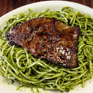 Linguini is lovingly sautéed in a creamy pesto sauce, creating a harmonious blend of herbs and cheese that coats each strand of pasta.